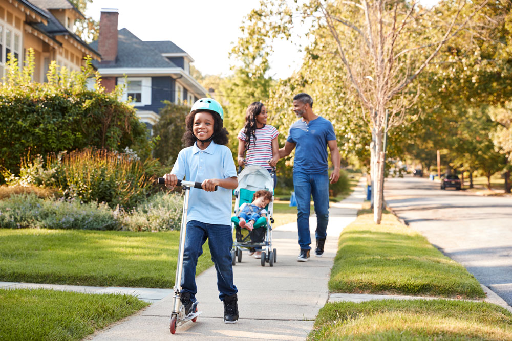 Family - parents and two children - walking down a neighbourhood/residential street
