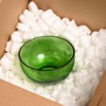 Loose fill in a cardboard box, protecting a green glass bowl