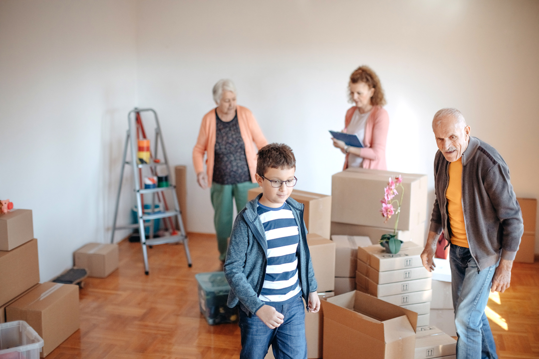 Family with senior members getting ready to move, surrounded by moving boxes