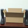 A pair of rain boots sit next to a 16x12x5 inch stock box