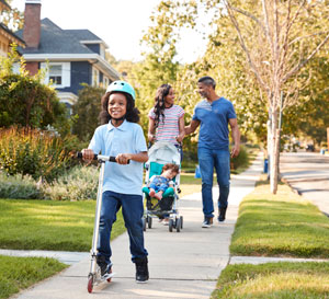 Family - parents and two children - walking down a neighbourhood/residential street